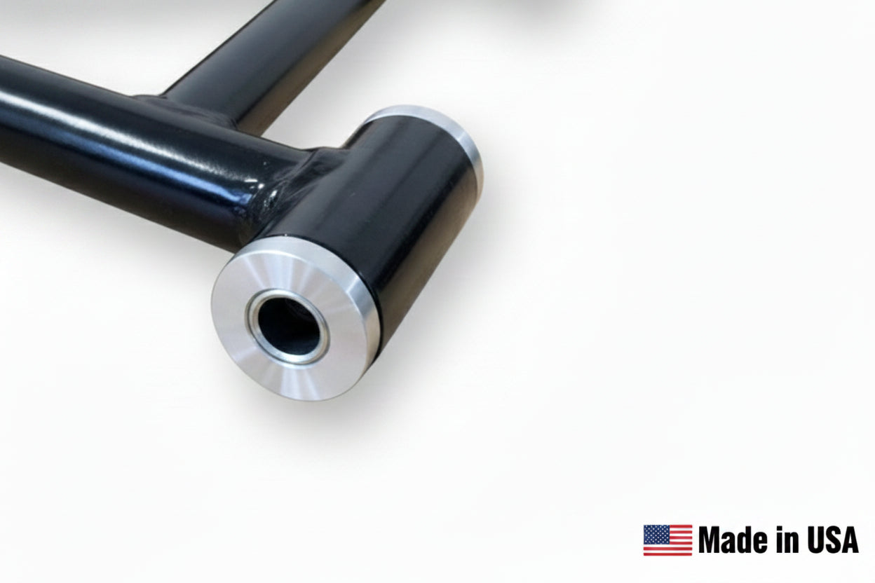 A close-up of a black steel suspension A-arm with a polished metal bushing insert, highlighting the rugged construction and "Made in USA" quality.