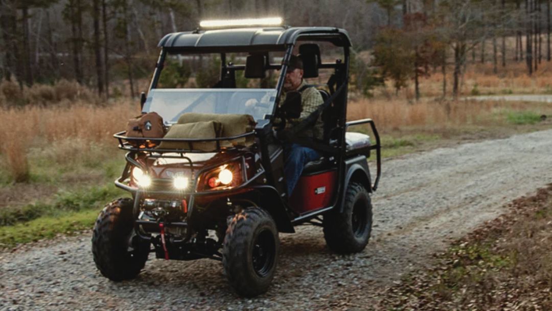Bad Boy Buggy driving on forest trail with headlights on. Guide to why it's clicking when pressing accelerator — what it means and how to fix it.