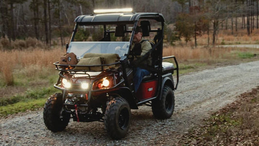 Bad Boy Buggy driving on forest trail with headlights on. Guide to why it's clicking when pressing accelerator — what it means and how to fix it.